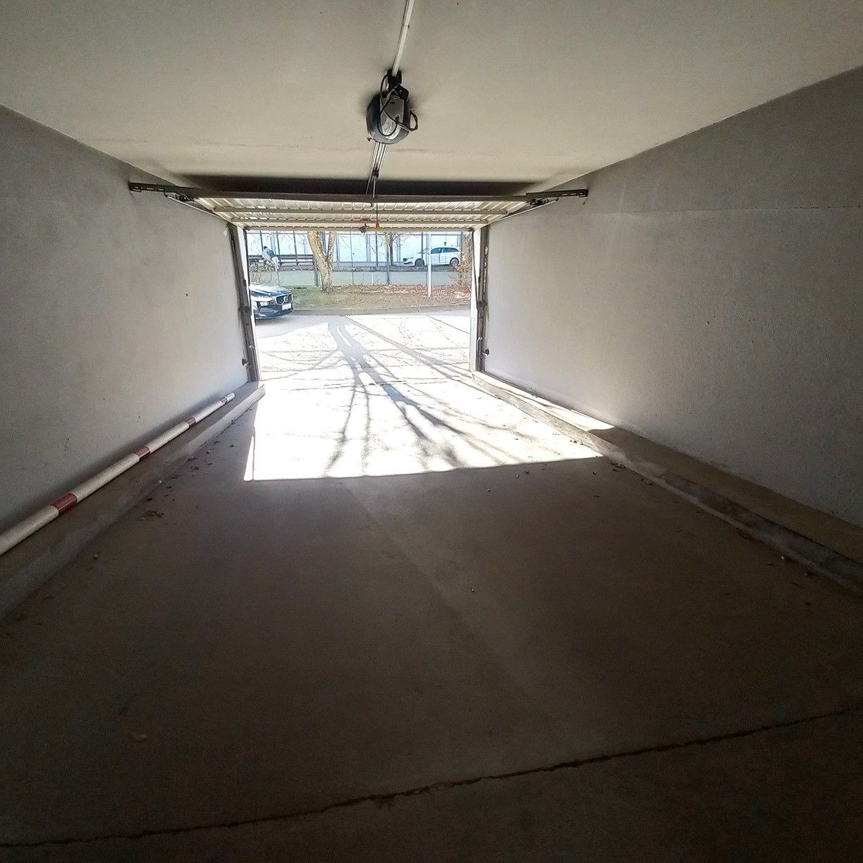 Prostorná garáž s betonovou podlahou a automatickými vraty, v dobrém stavu, ideální pro pohodlné parkování a uskladnění vozidel