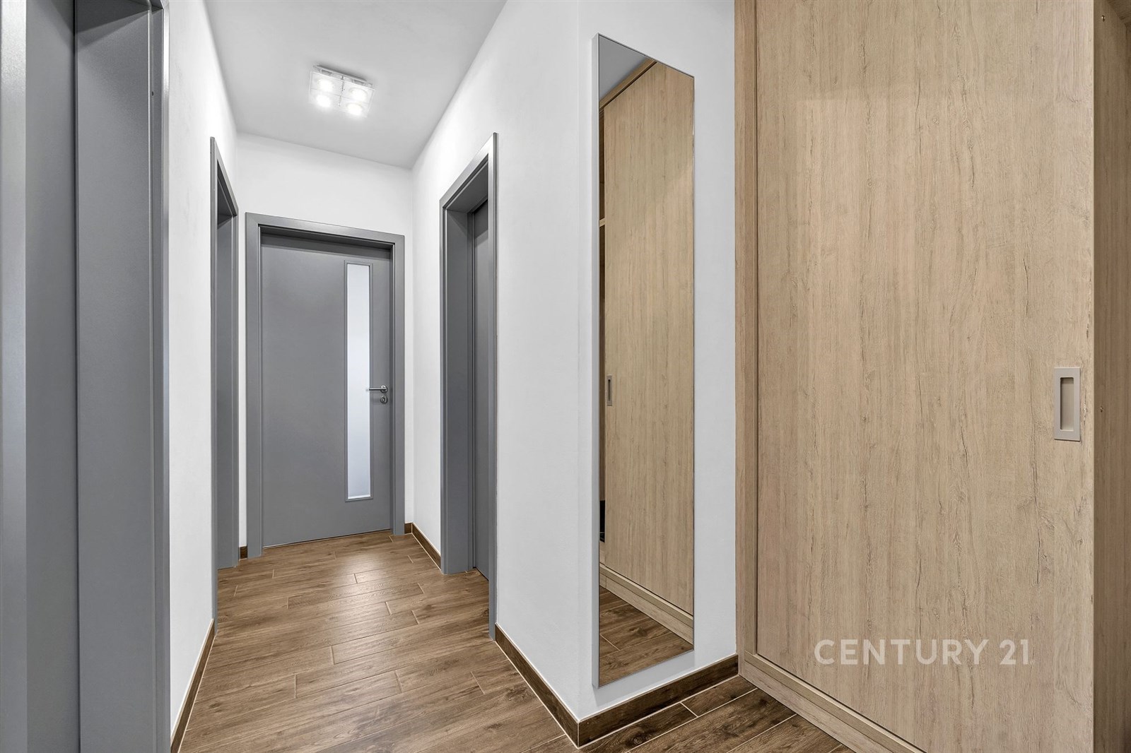 Úzká chodba s parketovou podlahou, velkým zrcadlem