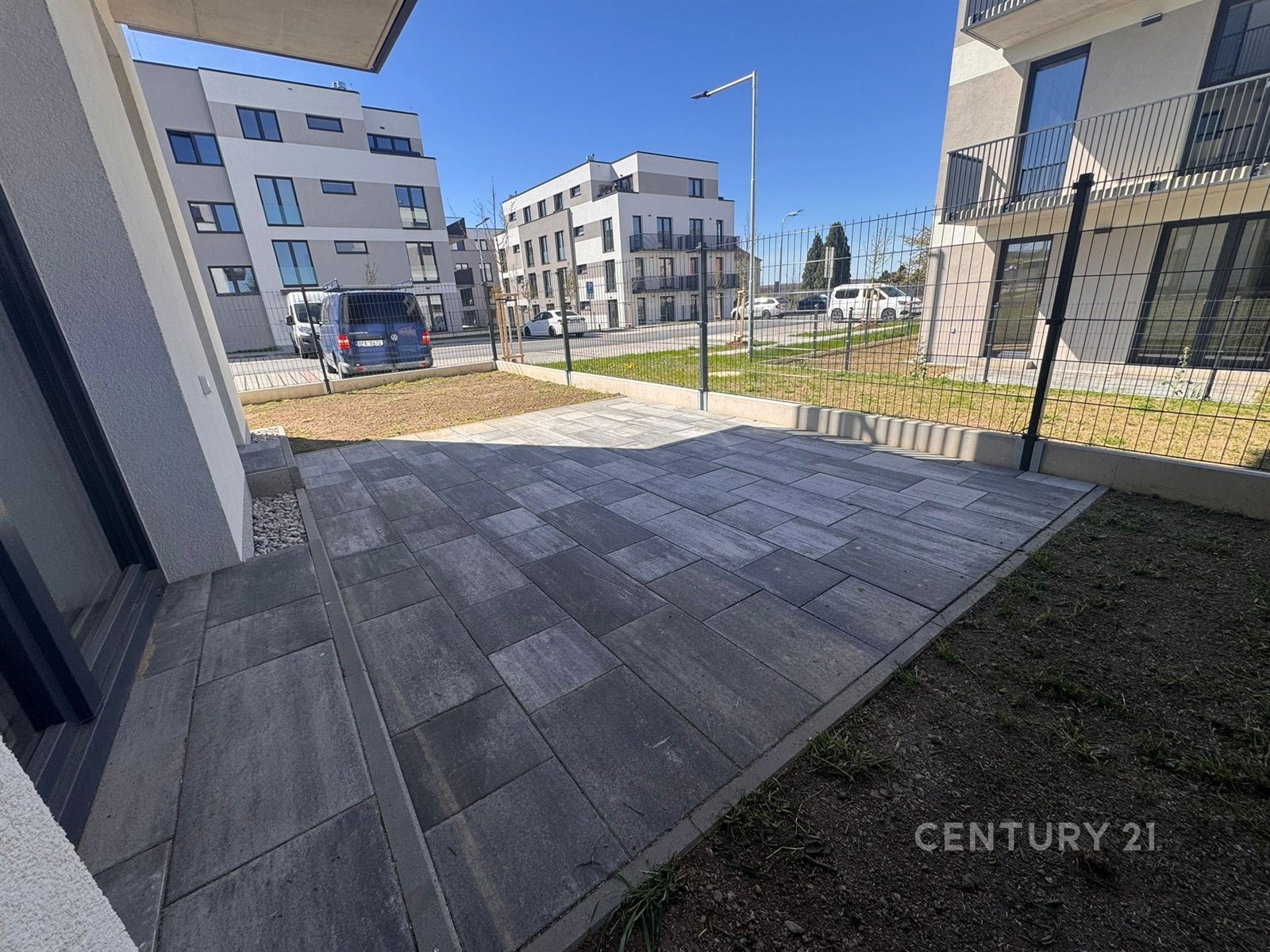 Terasa s moderní dlažbou, obklopena novostavbami a