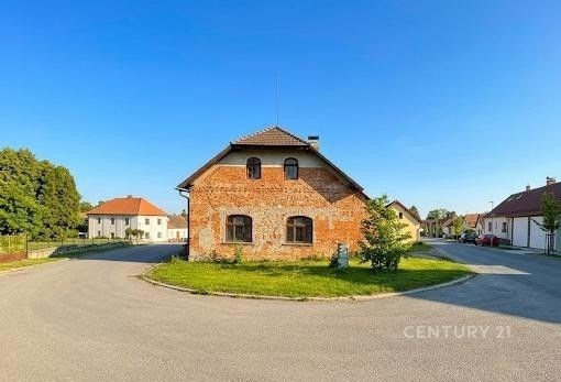Zrekonstruovaný cihlový dům s šikmou střechou a moderní fasádou se nachází na klidné ulici s asfaltovou příjezdovou cestou a zeleným okolím.