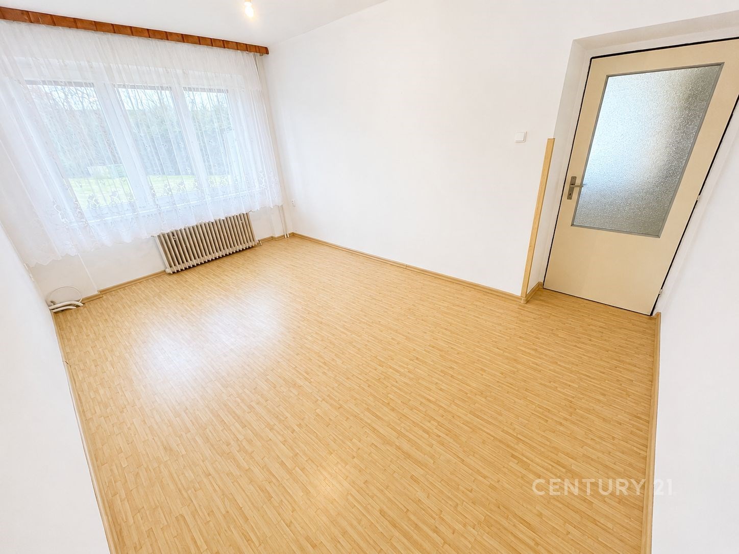 Světlý pokoj s laminátovou podlahou, velkými okny 