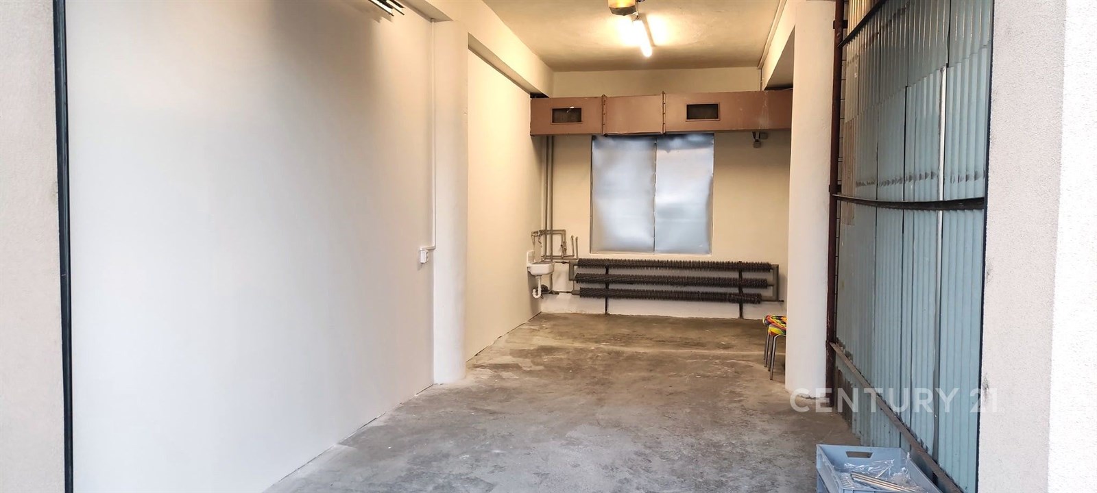 Úzká garáž se surovou betonovou podlahou, plechová