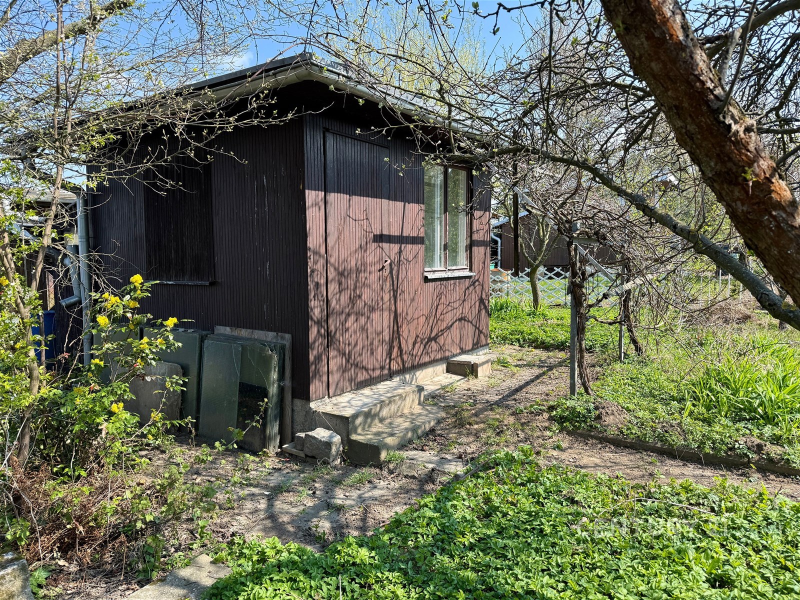 Malá zahradní chatka ze dřeva, situovaná v klidné 