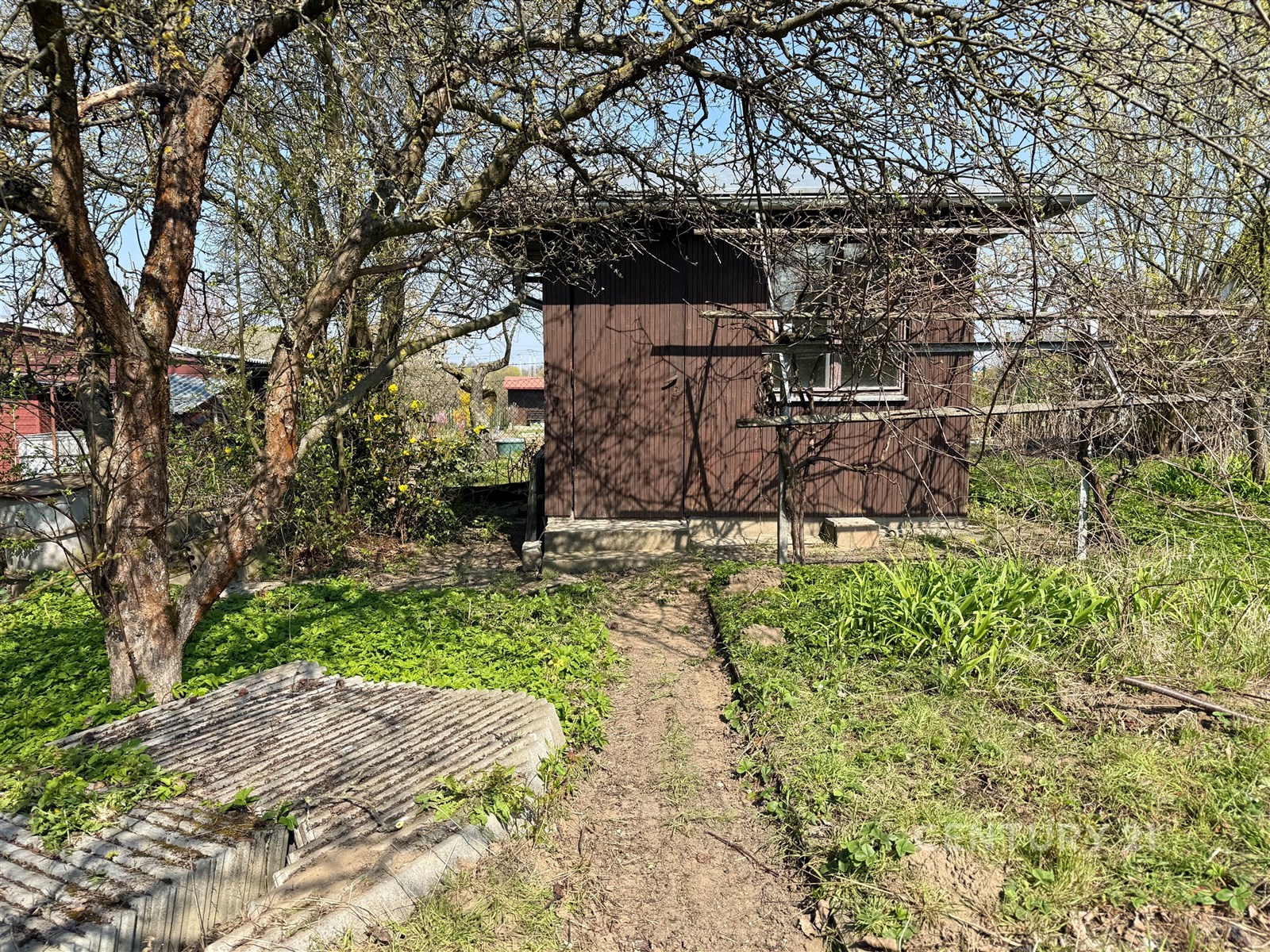 Malá zahradní chatka s dřevěnou fasádou uprostřed 