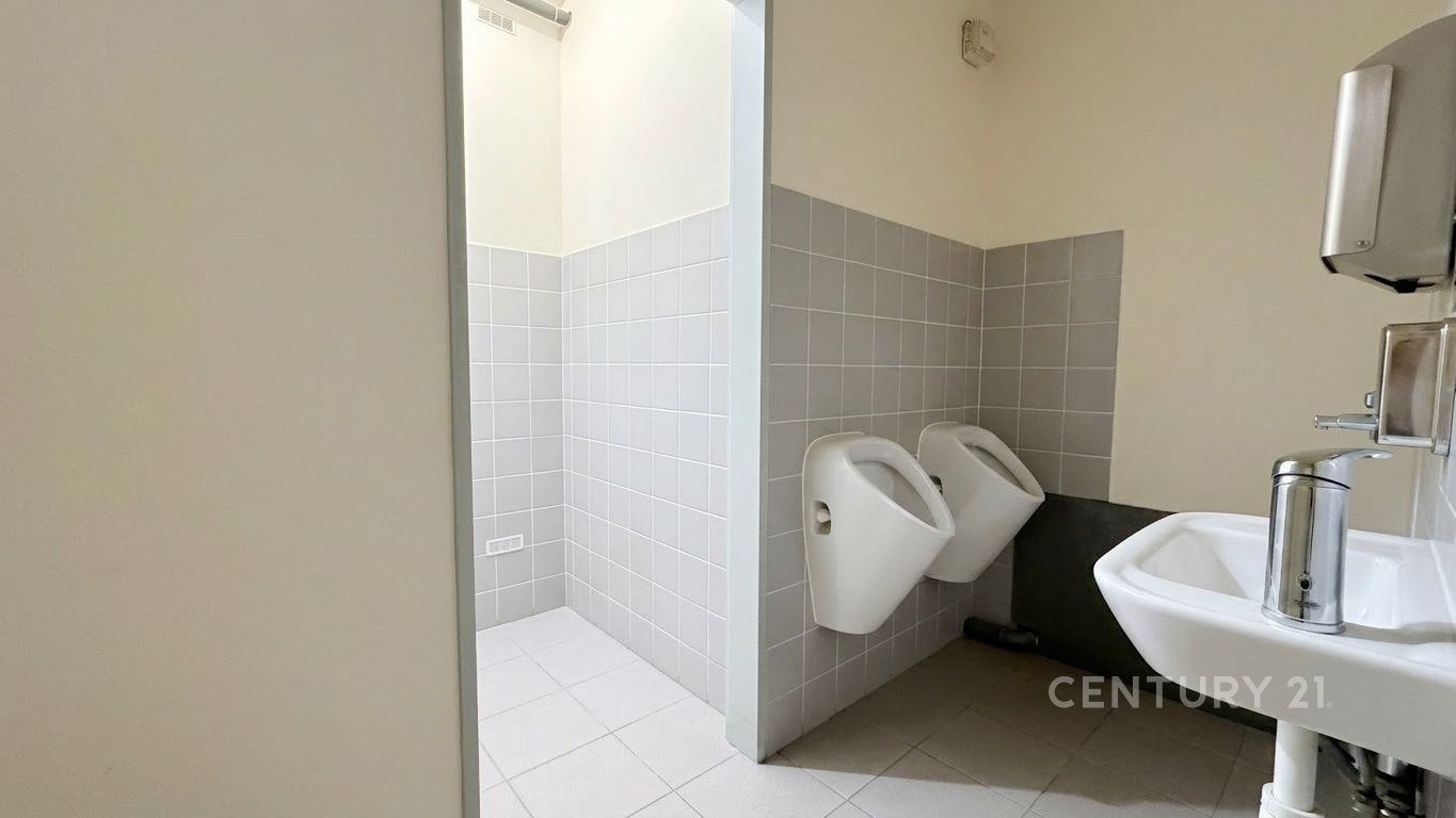 Veřejné toalety s bílou keramickou dlažbou, světlými obklady a dvěma pisoáry. Moderní sanitární vybavení a jednoduchý design.