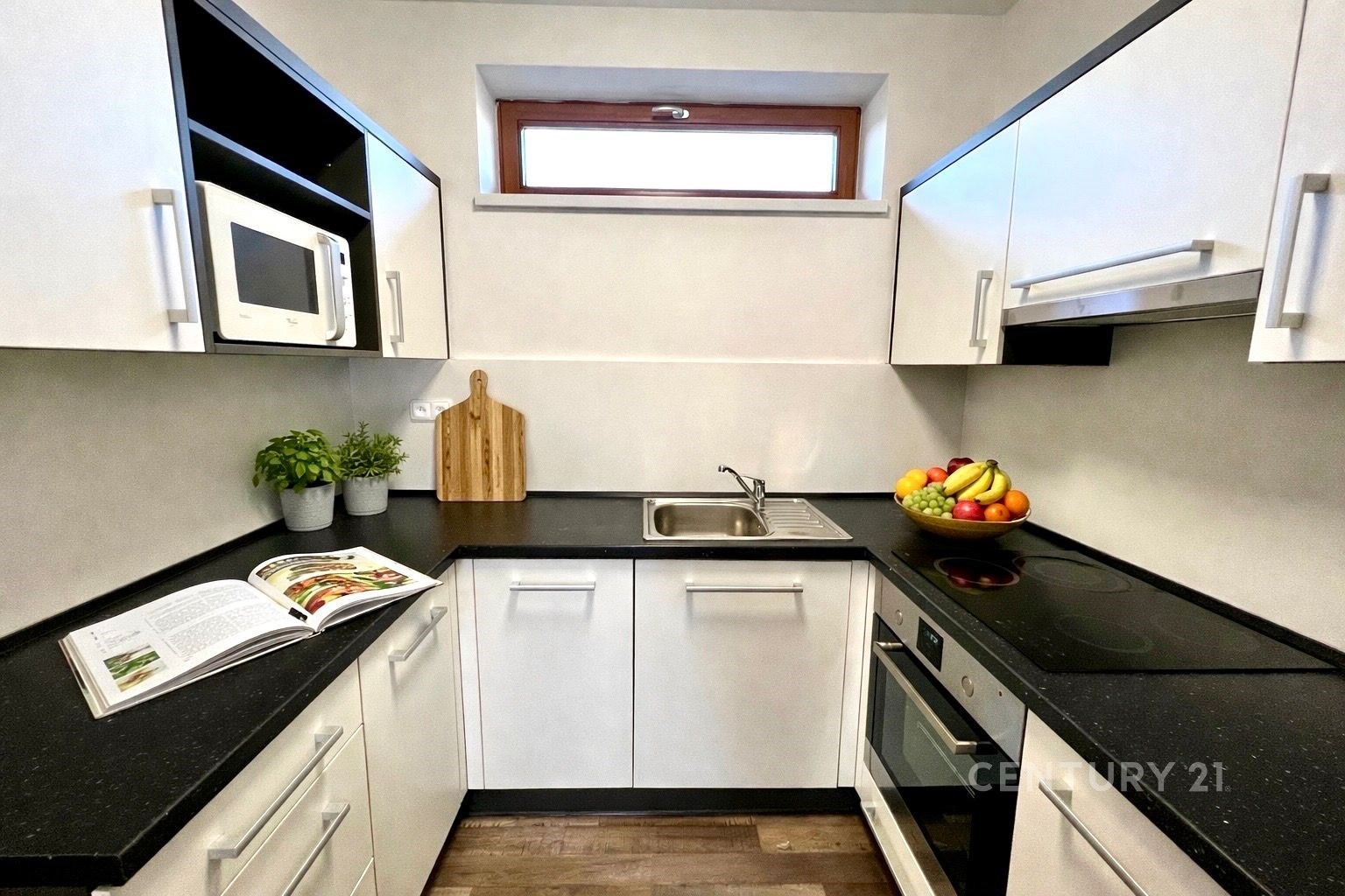 Moderní kuchyň s bílými skříňkami, černou pracovní