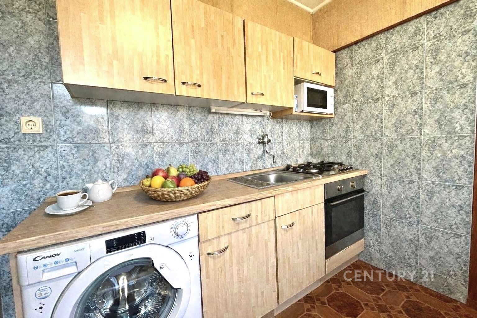 Kompaktní kuchyň s dřevěnými skříňkami, dlažbou a 