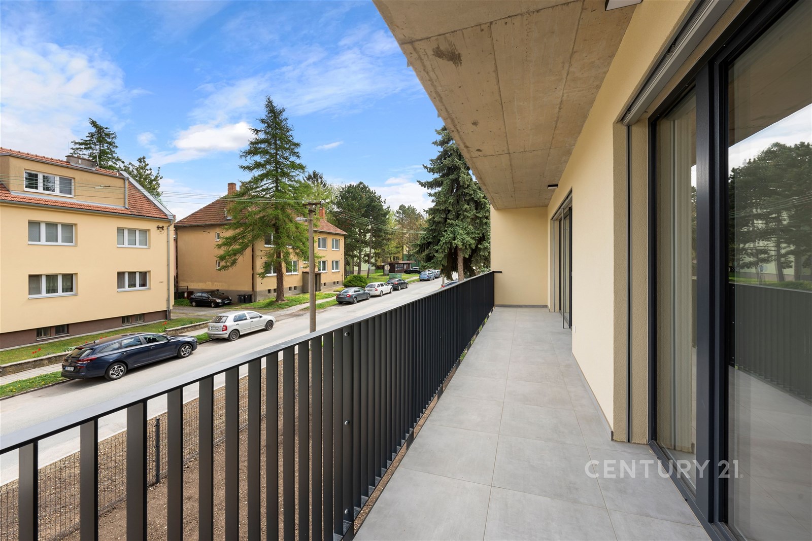 Prostorný balkon s dlažbou, moderním zábradlím a v