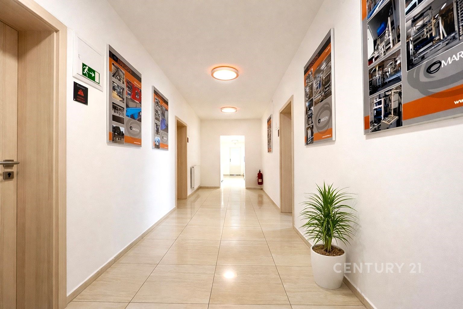 Dlouhá chodba s dlažbou, světlá stěna, moderní osv