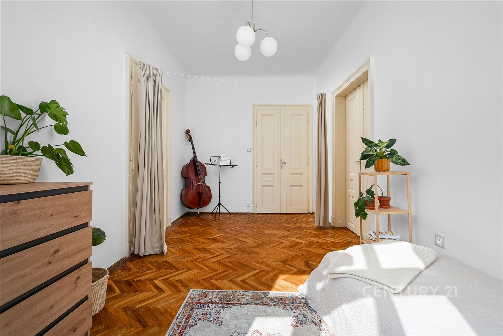 Světlá ložnice s parketovou podlahou a bílými zdmi