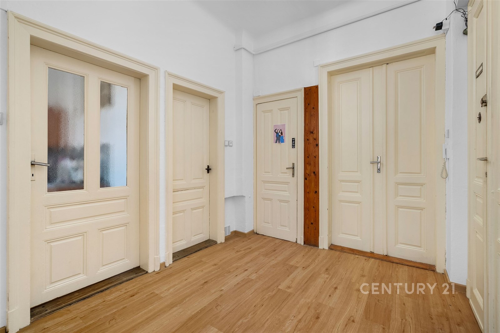 Chodba s parketovou podlahou, světlými dveřmi a bí