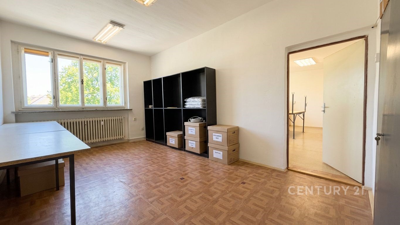 Prostorná pracovna s parketovou podlahou, světlé stěny, velká okna, minimalistický design, úložný prostor, ideální pro kancelářské využití.