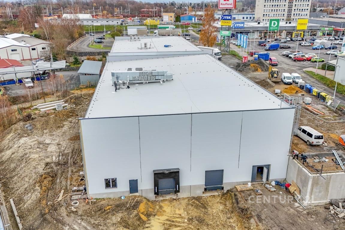 Průmyslová hala s moderní fasádou, nacházející se v komerční zóně poblíž nákupního centra, nabízí prostorné řešení pro skladování či výrobu.