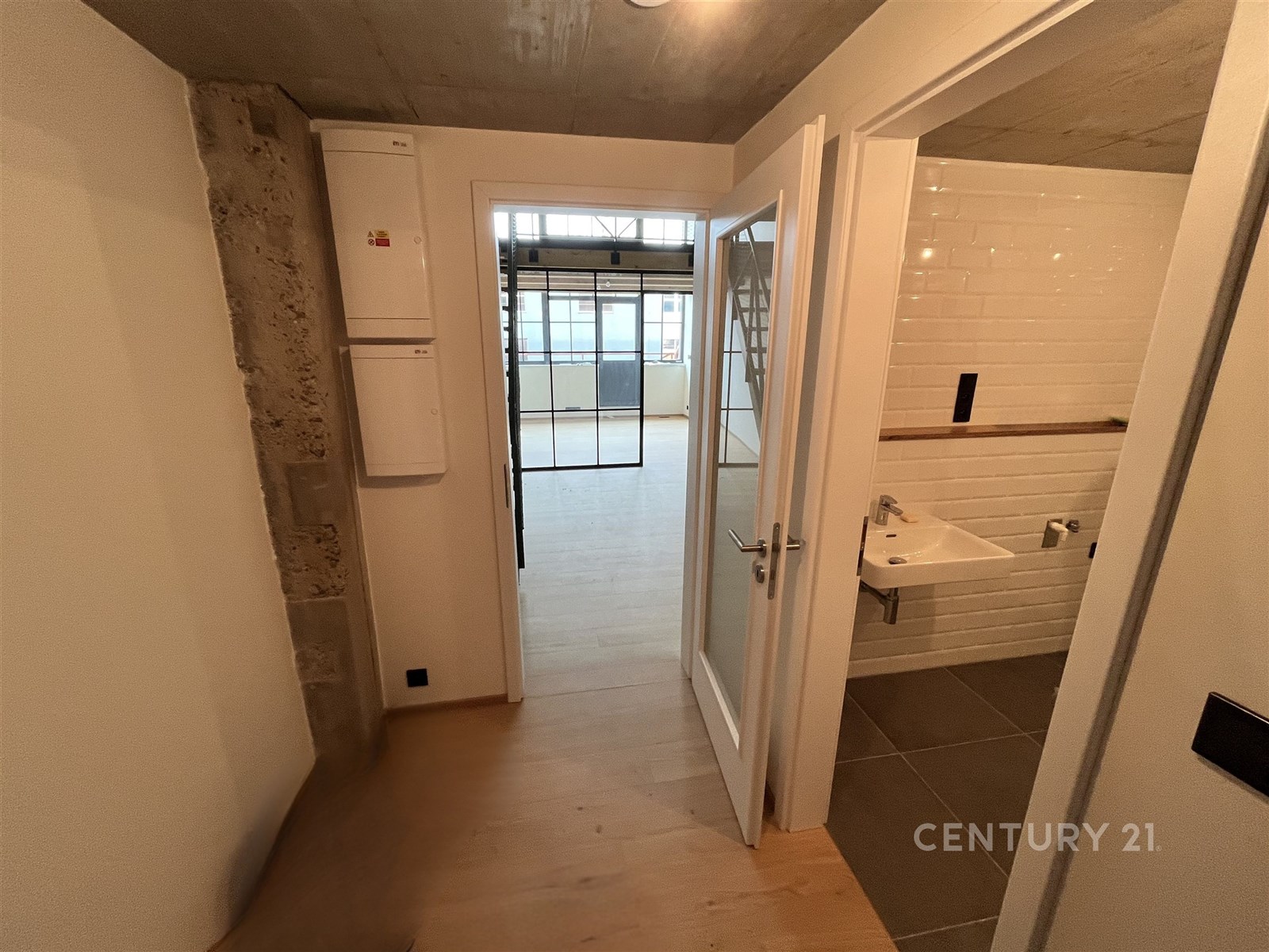 Chodba s dřevěnou podlahou, odkrytou betonovou stě