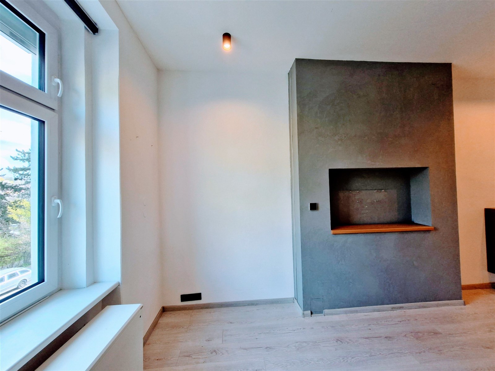 Světlý obývací pokoj s parketovou podlahou, velkým