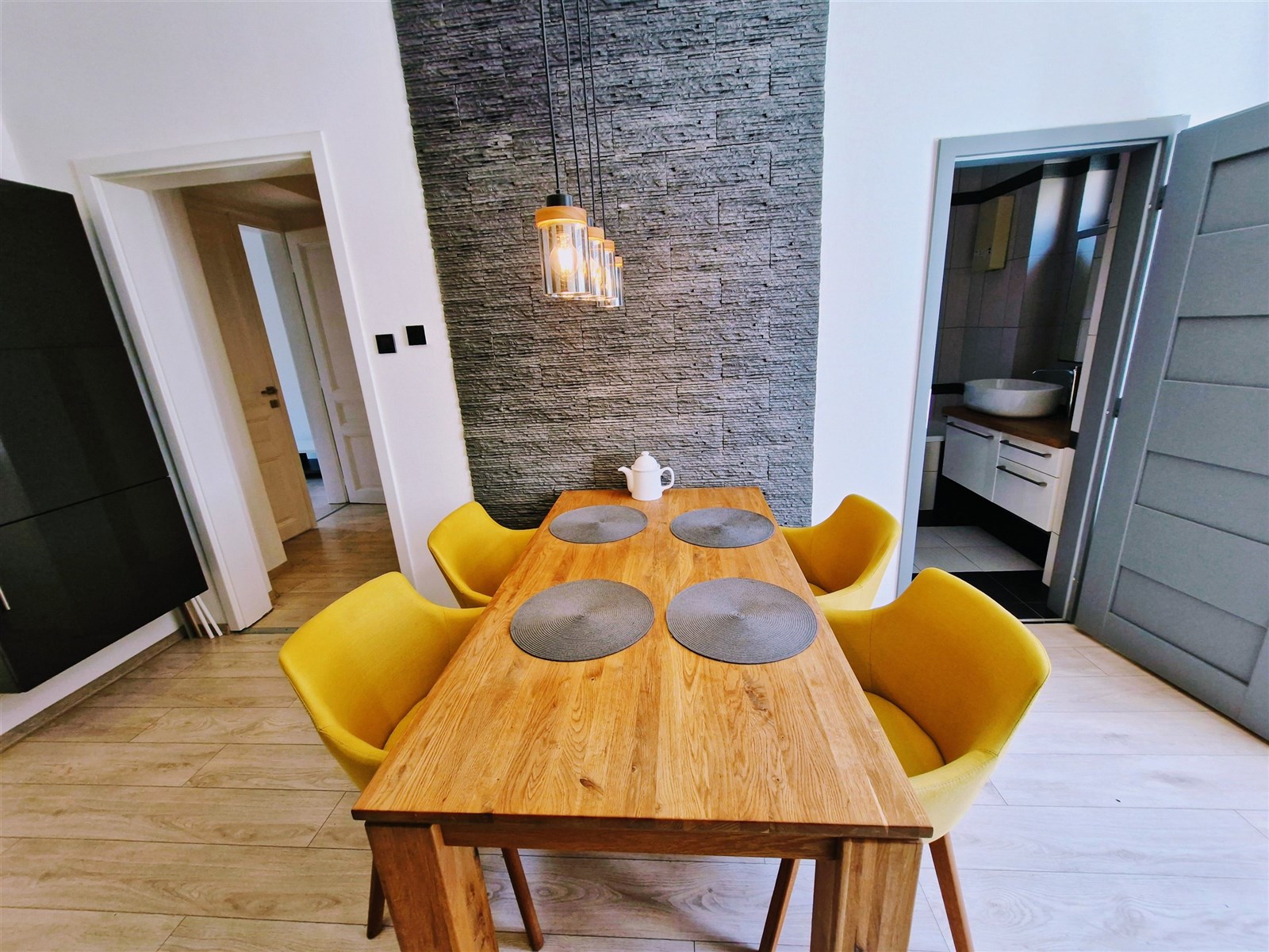 Jídelna s dřevěným stolem a žlutými židlemi, kamen