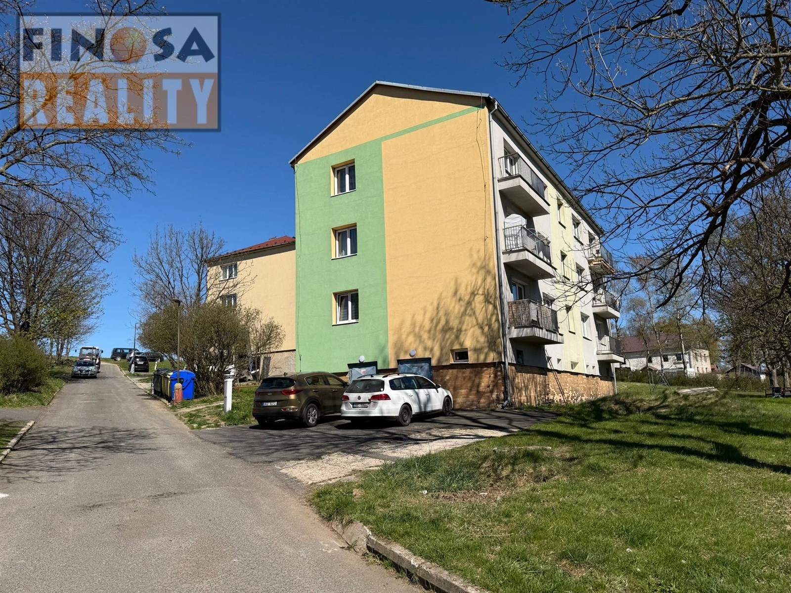 Vícepodlažní bytový dům se zeleno-žlutou fasádou, 