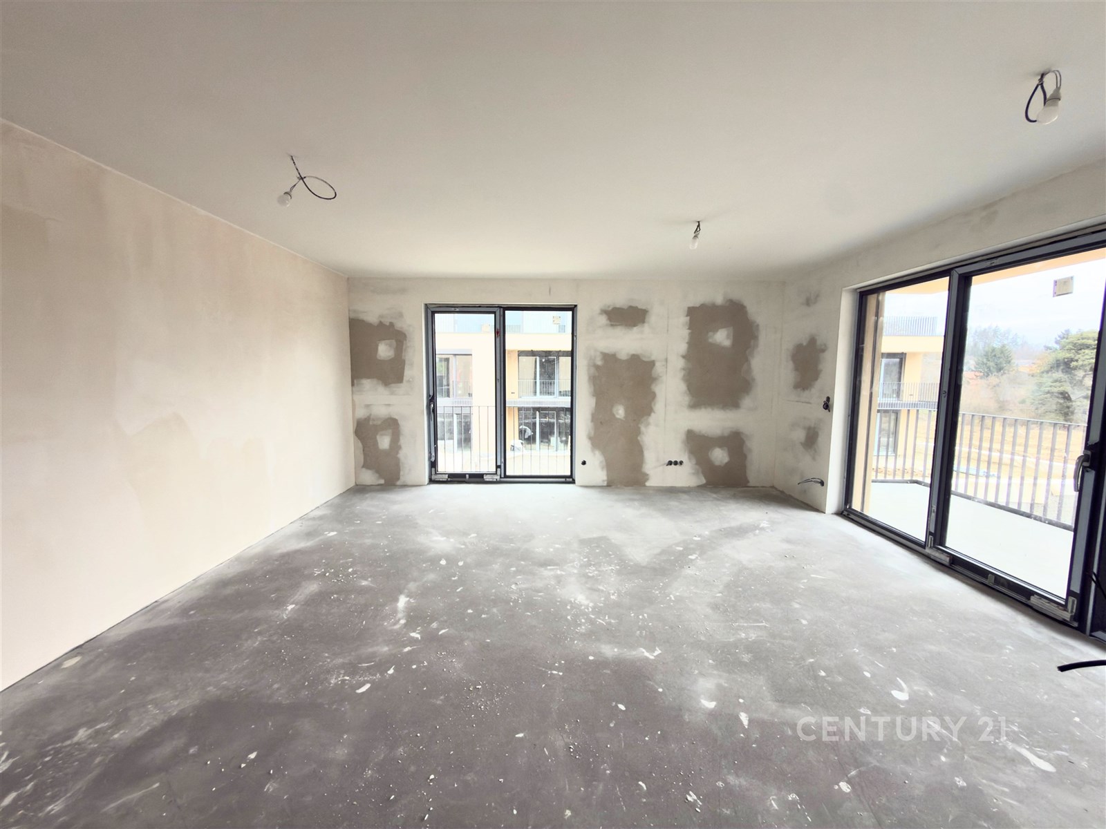 Prostorný obývací pokoj s velkými okny, betonovou 