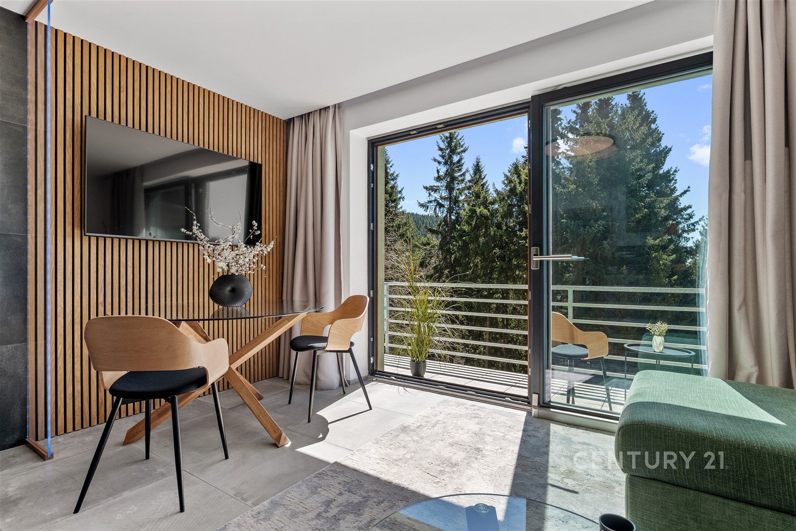 Moderní obývací pokoj s velkými okny a přístupem na balkon, dlažba na podlaze, dřevěné dekorace stěn, prosvětlený interiér