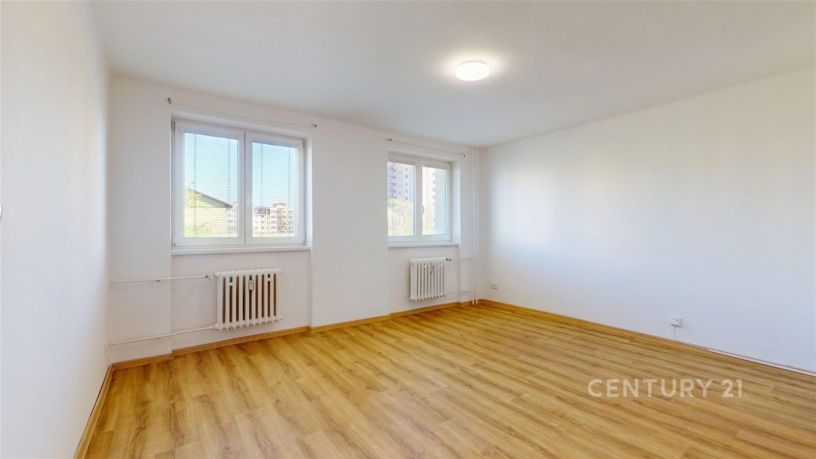 Světla ložnice s dřevěnou podlahou, velkými okny a moderním designem.