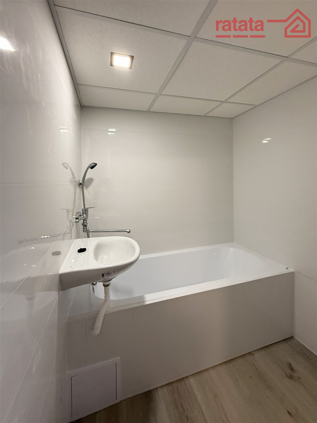 Moderní koupelna s vanou, světle šedá dlažba, minimalistické obklady, bodové osvětlení, útulný design pro pohodlné bydlení