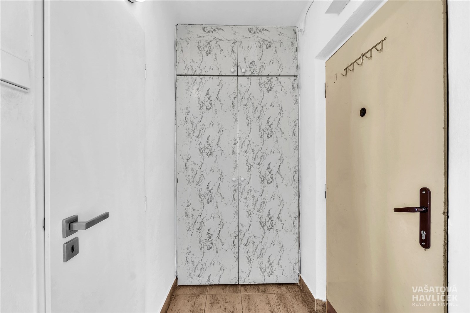 Vstupní chodba s dřevěnou podlahou, mramorovou vestavěnou skříní a bíle natřenými stěnami, poskytující světlé a moderní prostředí.