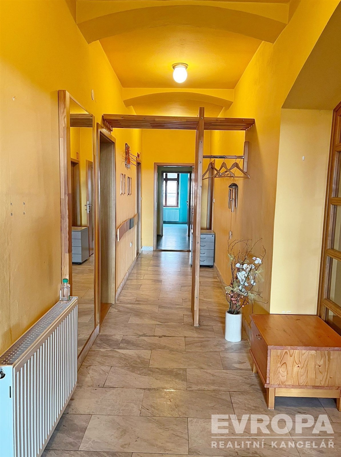 Dlouhá chodba s dlažbou, dřevěné prvky a vestavěné skříně, světlé stěny, dobrý stav