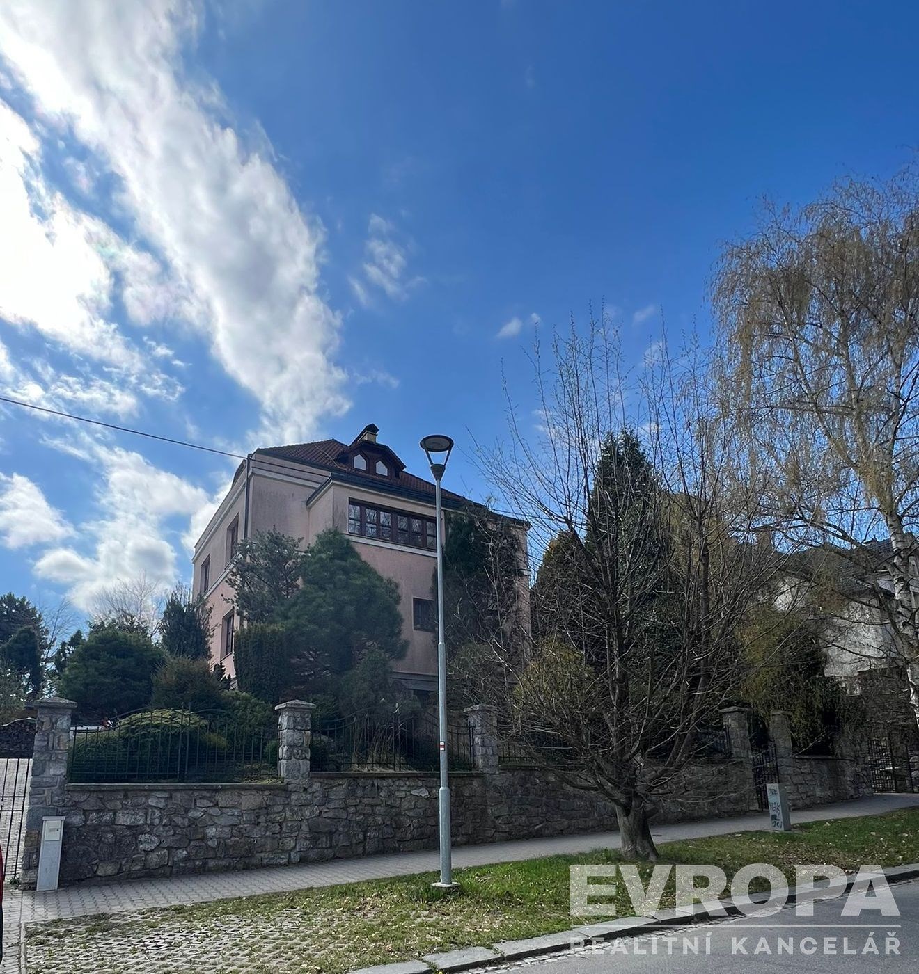 Vila s kamenným plotem, zasazená v udržované zahra