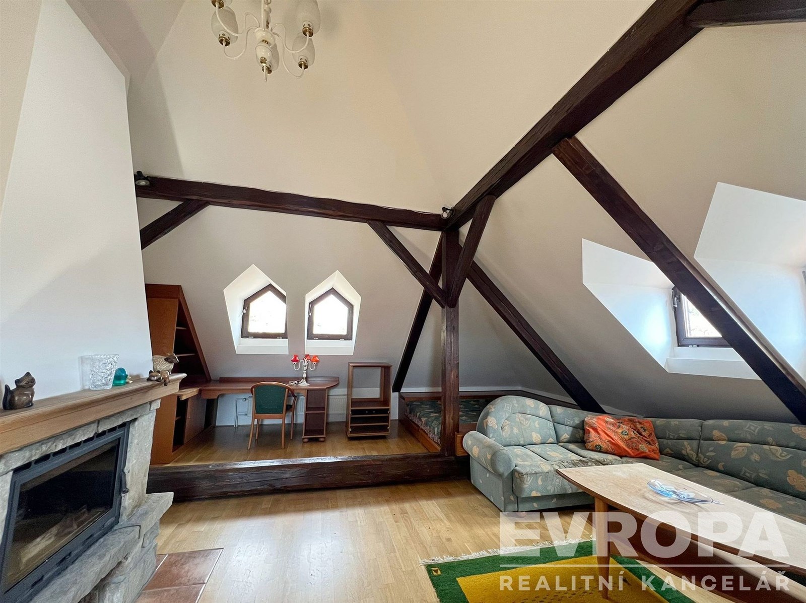 Podkrovní obývací pokoj s dřevěnými trámy, krbovým