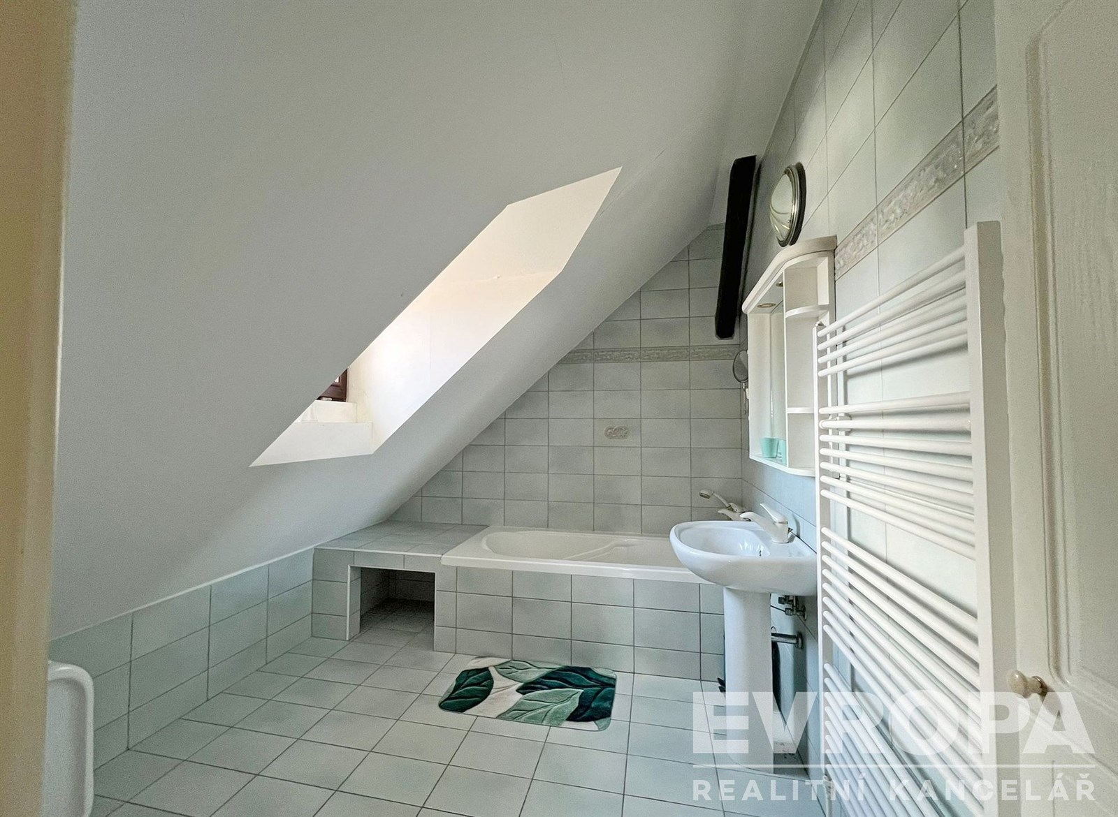 Podkrovní koupelna s keramickou dlažbou, vanou a s