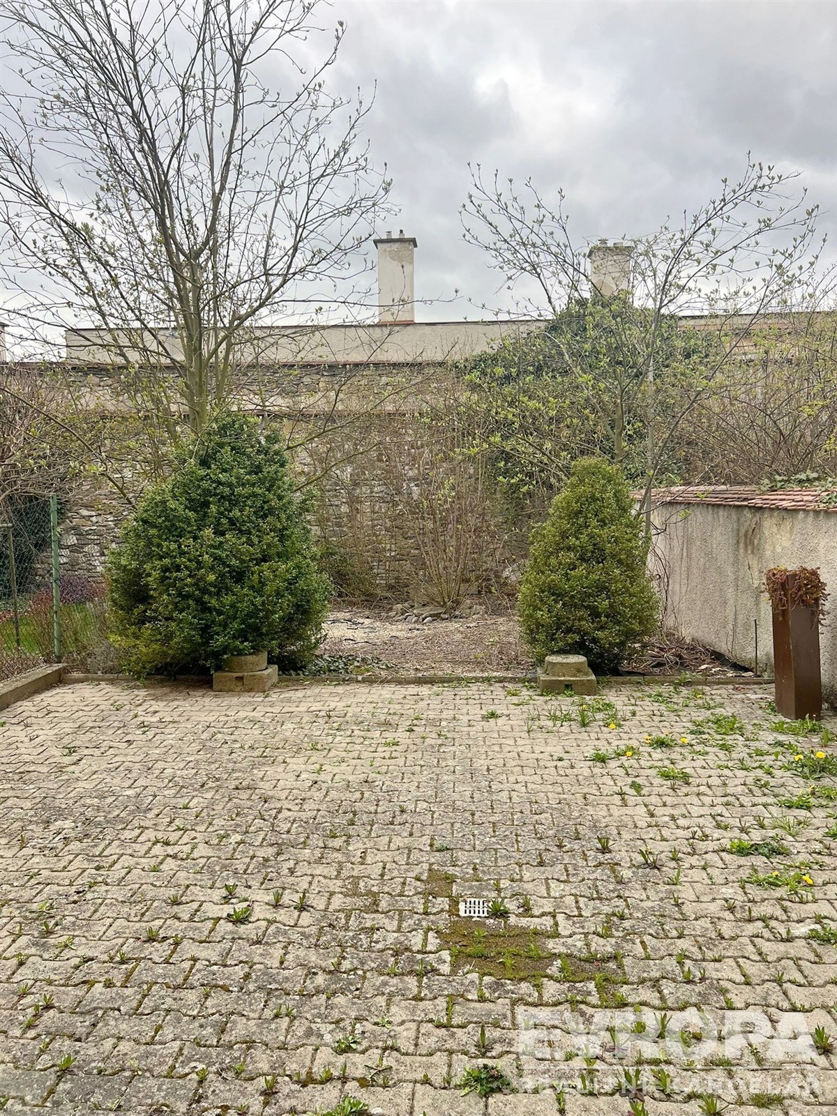 Dlážděná zahrada s kamennou dlažbou, obklopena zelení, ideální pro venkovní relaxaci, nabízí soukromí a klidnou atmosféru.