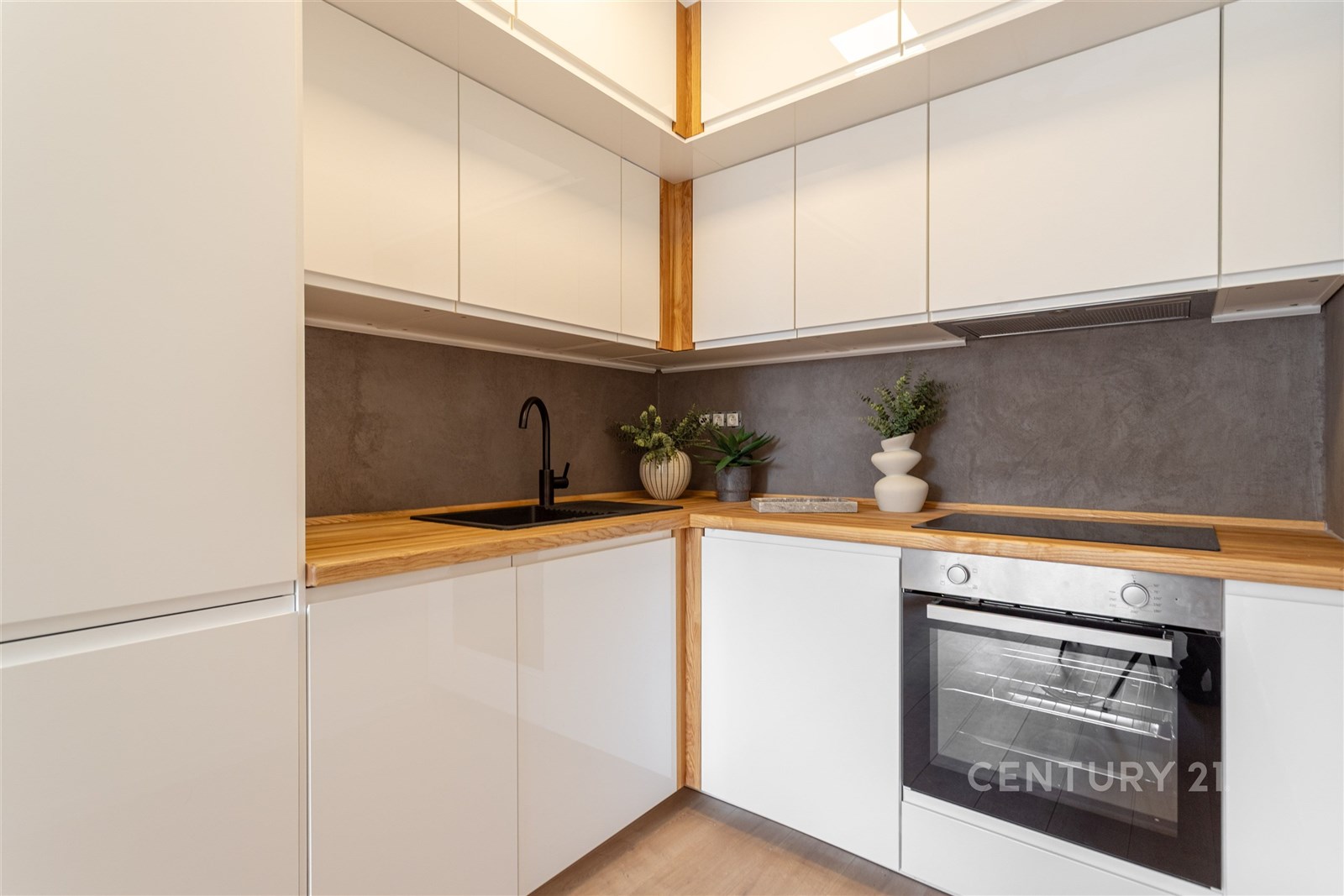 Moderní kuchyň, světlé skříňky s dřevěnou pracovní deskou, elegantní černá armatura, vestavěná trouba, minimalistický design