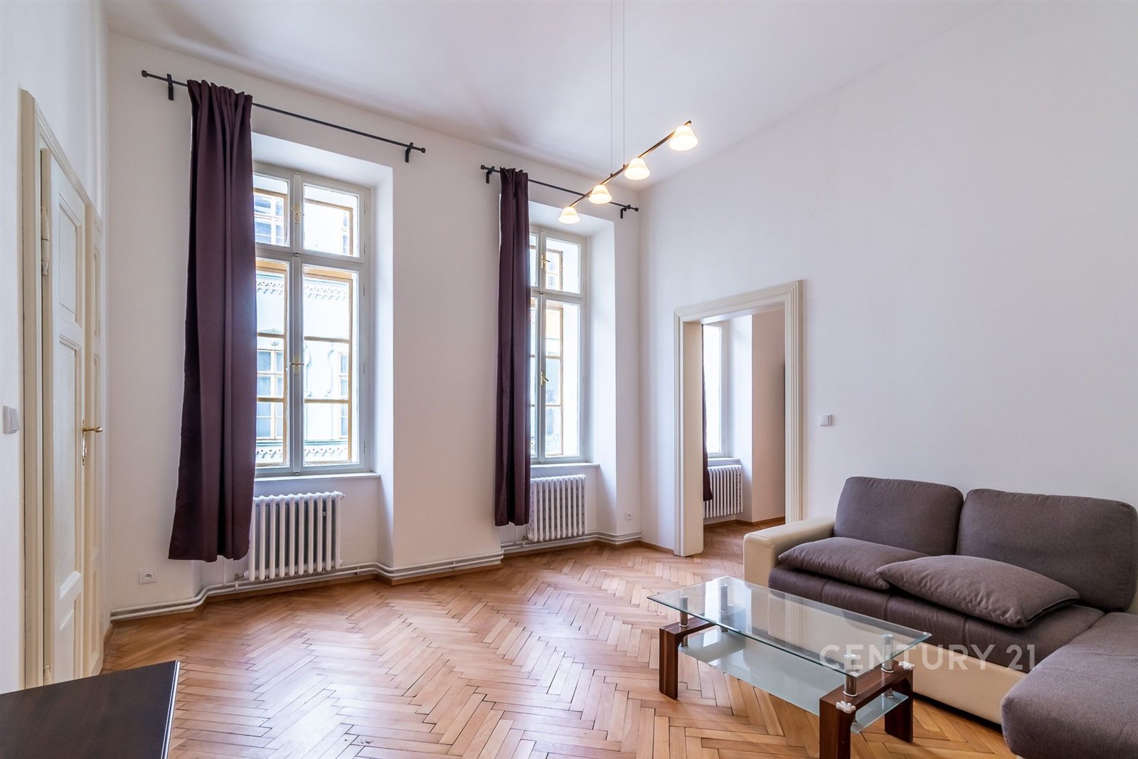 Prostorný obývací pokoj, parketová podlaha, velká okna, moderní design, světlý interiér, ideální pro rodinné bydlení.