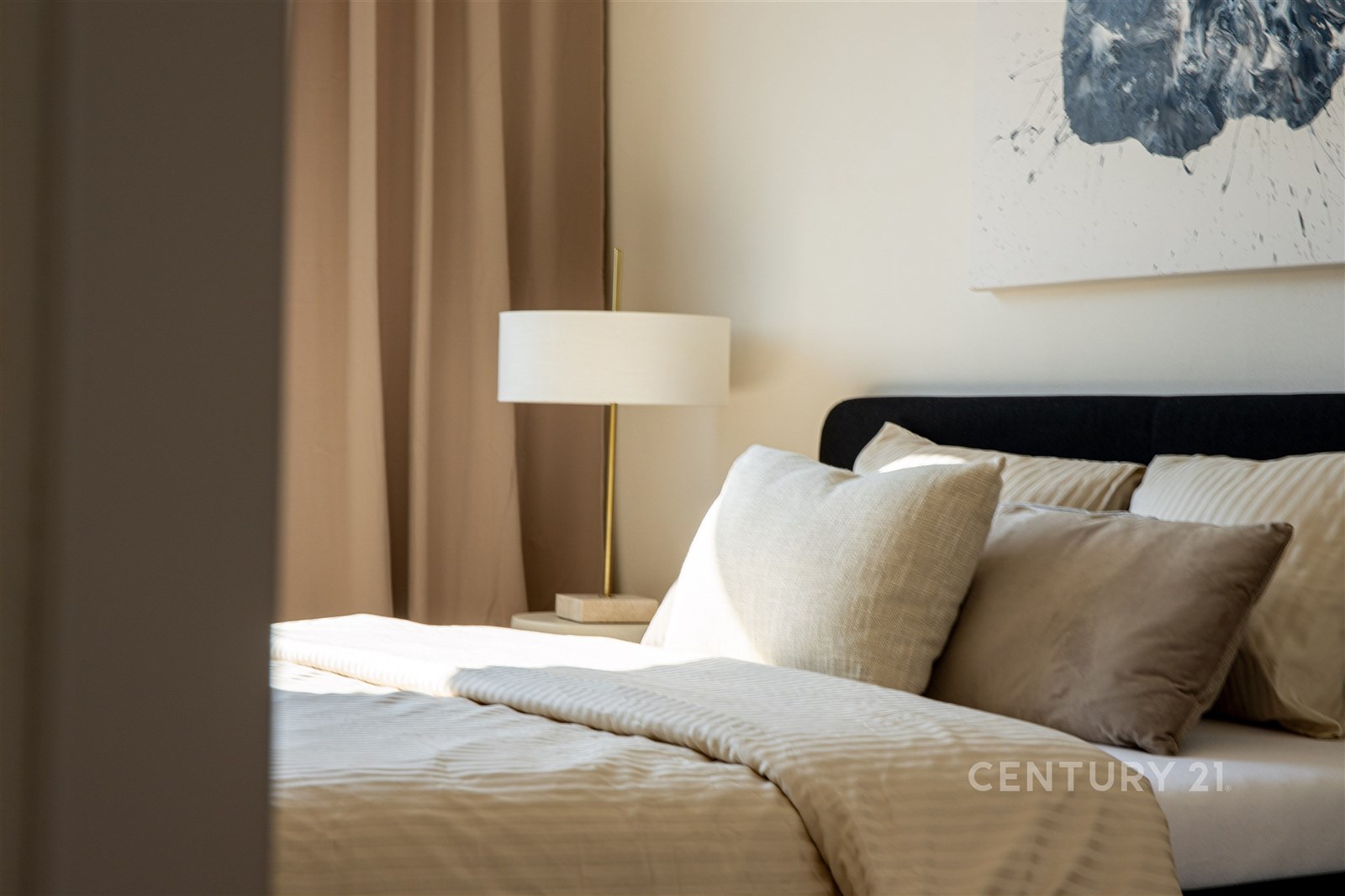 Prostorná ložnice s moderním designem, světlé ložní prádlo a tlumené osvětlení, velká okna zajišťují dostatek denního světla.