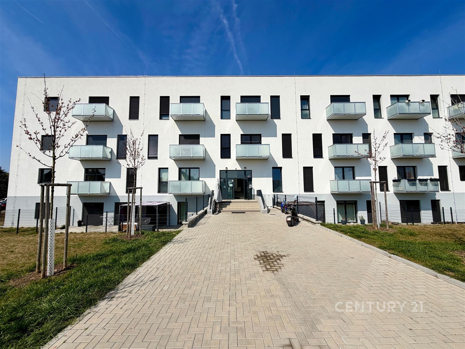 Moderní bytový dům s balkony, minimalistická architektura, světlá fasáda, nový development v klidné lokalitě.