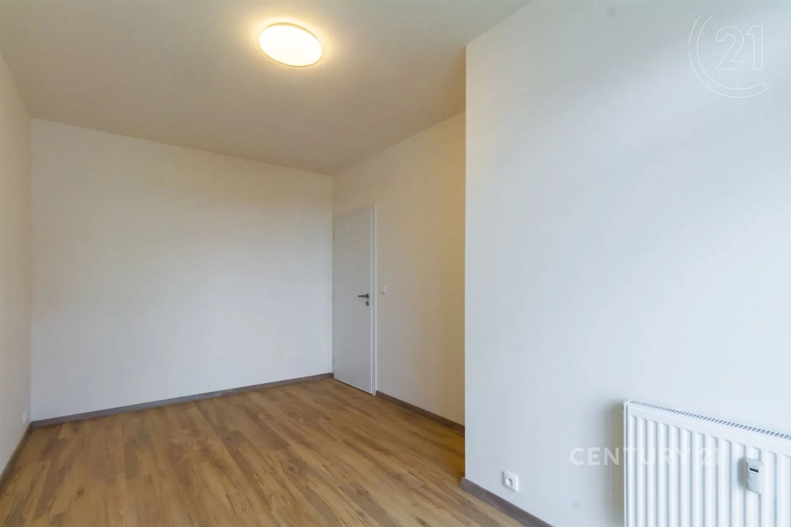 prázdná místnost s radiátor a dřevěná podlaha