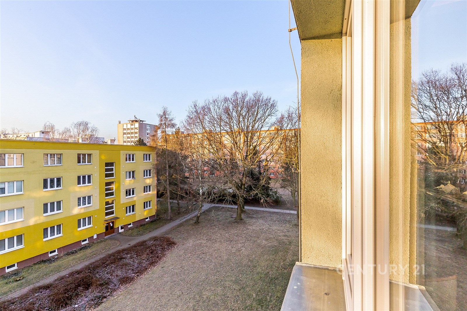 Výhled z okna na světlý exteriér, žlutá fasáda bud