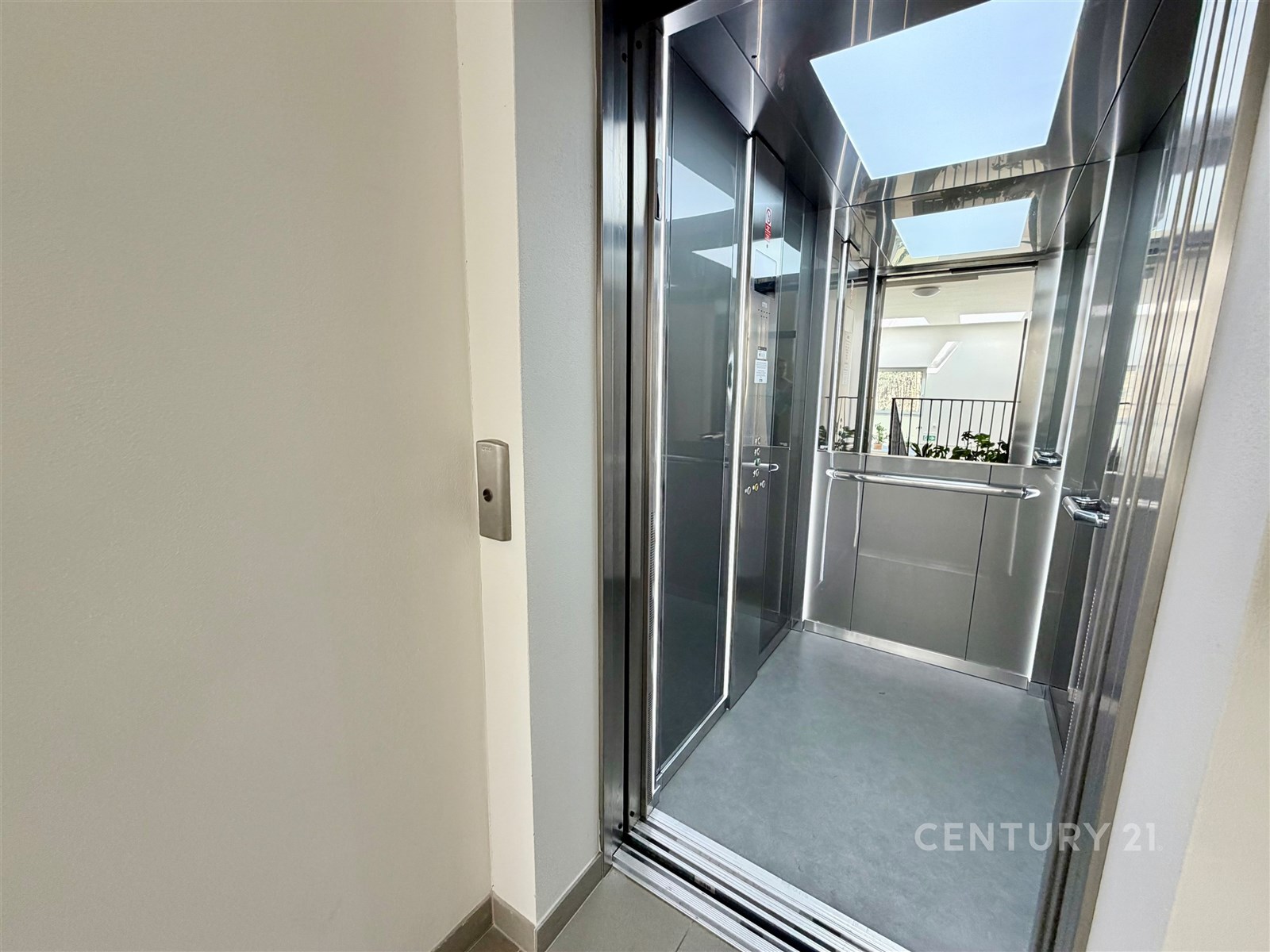 Moderní výtah s nerezovými stěnami a velkým střešním světlíkem, poskytující dostatek přirozeného světla, ideální pro pohodlný přístup.
