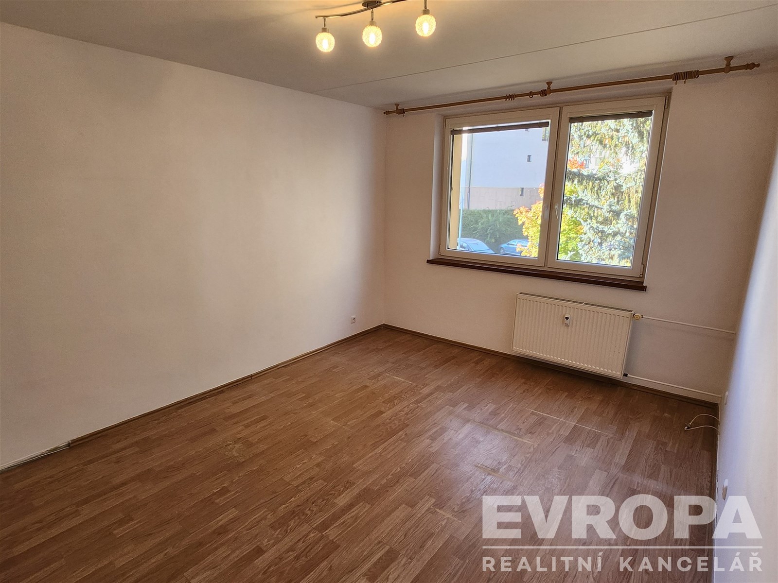 prázdná místnost s sledovat osvětlení, přirozené světlo, dřevěná podlaha, a radiátor