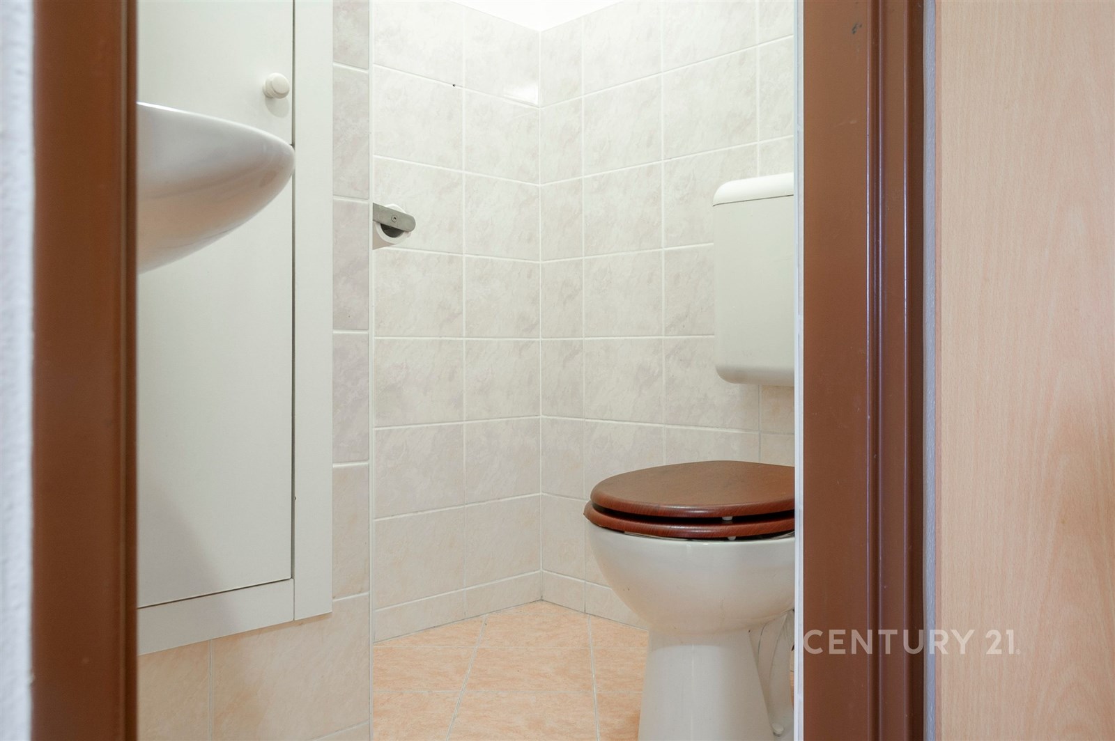 Malá koupelna s dlažbou a obklady, světlé keramické dlaždice, moderní bílé sanitární zařízení, nově rekonstruovaný prostor.