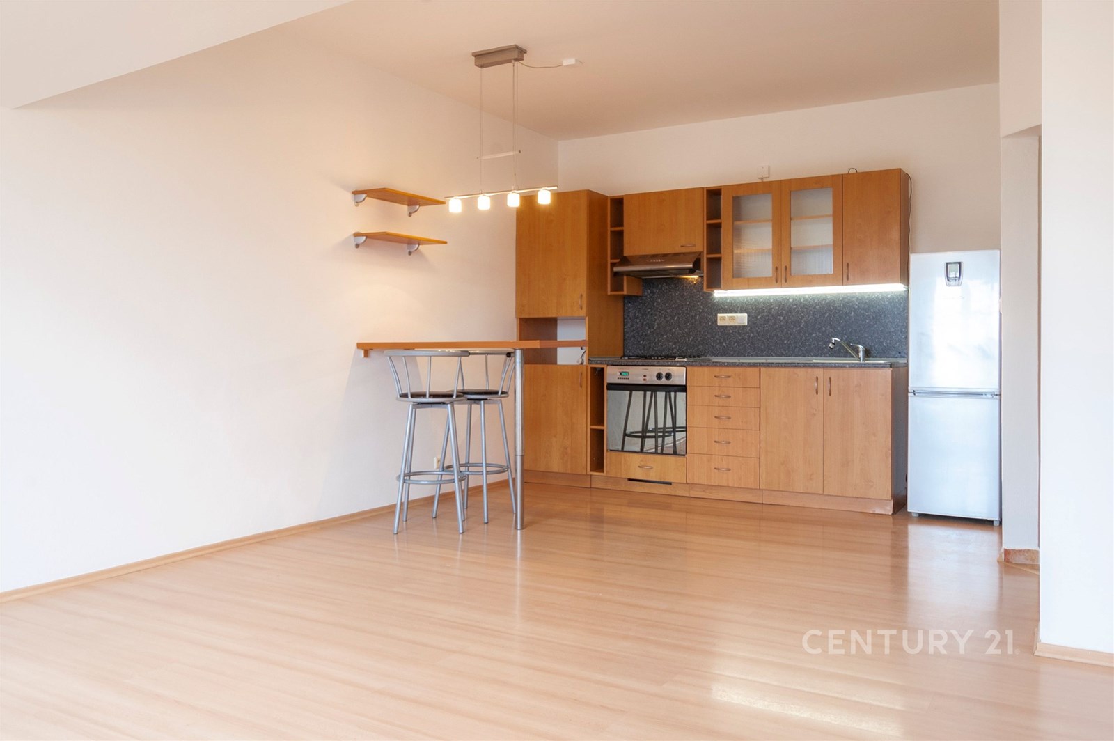 Kuchyňský kout s parketovou podlahou, moderní spotřebiče, dřevěné skříňky a vestavěná kuchyňská linka v světlém bytě.