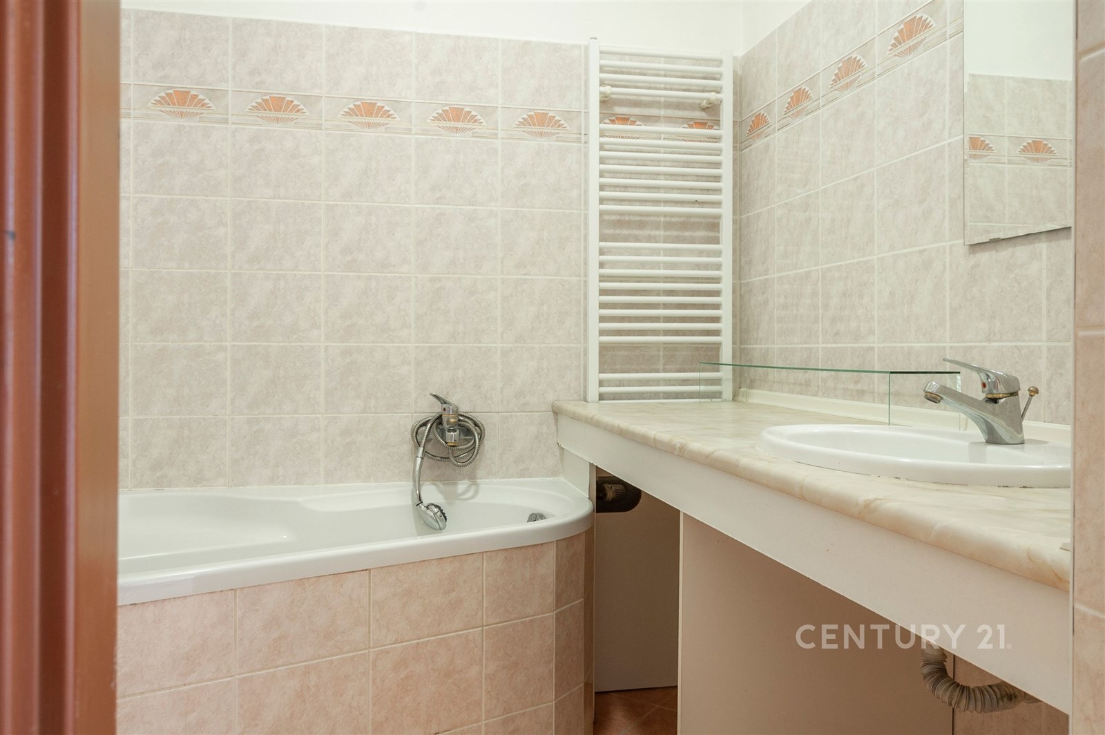 Koupelna s dlažbou, moderní umyvadlo s pákovou baterií, vana a topný žebřík, světlé obklady a zrcadlo vytvářejí pocit prostornosti.