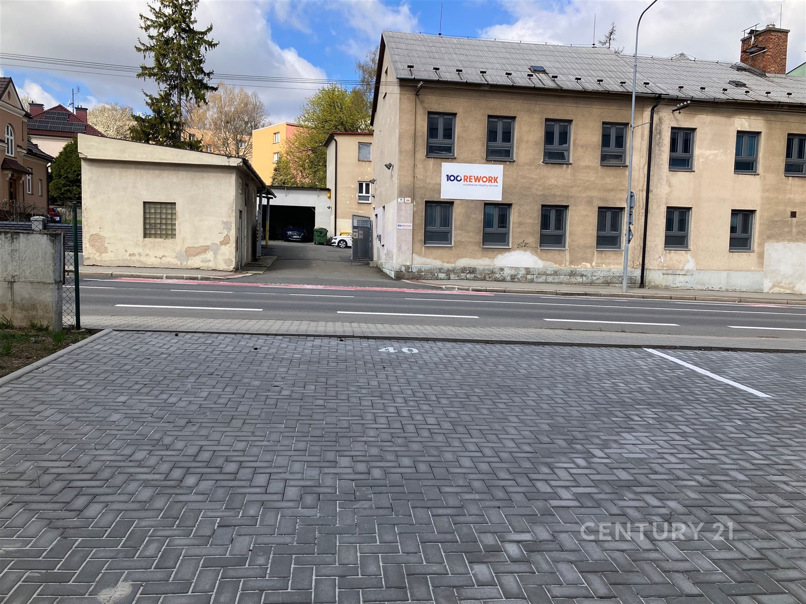 Prázdné parkoviště s dlážděným povrchem se nachází před průmyslovou budovou. Vhodné pro komerční využití, dobrý přístup.