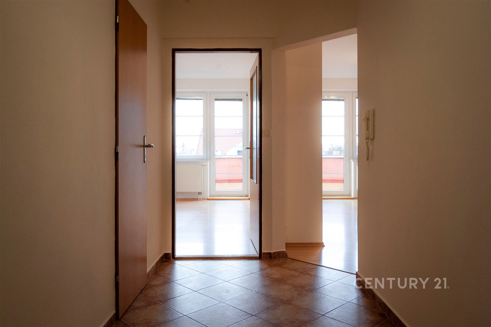 Vstupní hala s dlažbou, vede do světlého obývacího pokoje s velkými okny. Moderní interiér s kvalitním materiálem podlah.