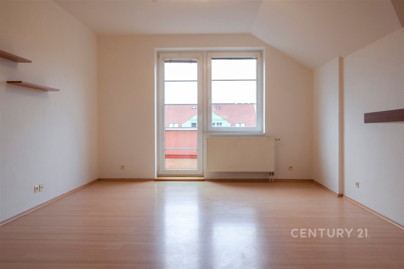 Prostorný obývací pokoj s parketovou podlahou, velká okna a moderní styl, ideální pro přirozené osvětlení a otevřený pocit prostoru.