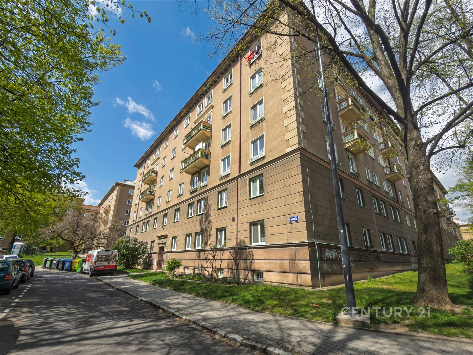 Exteriér bytového domu se zateplenou fasádou, balkony a udržovanými veřejnými prostory, klidná lokalita poblíž centra města.
