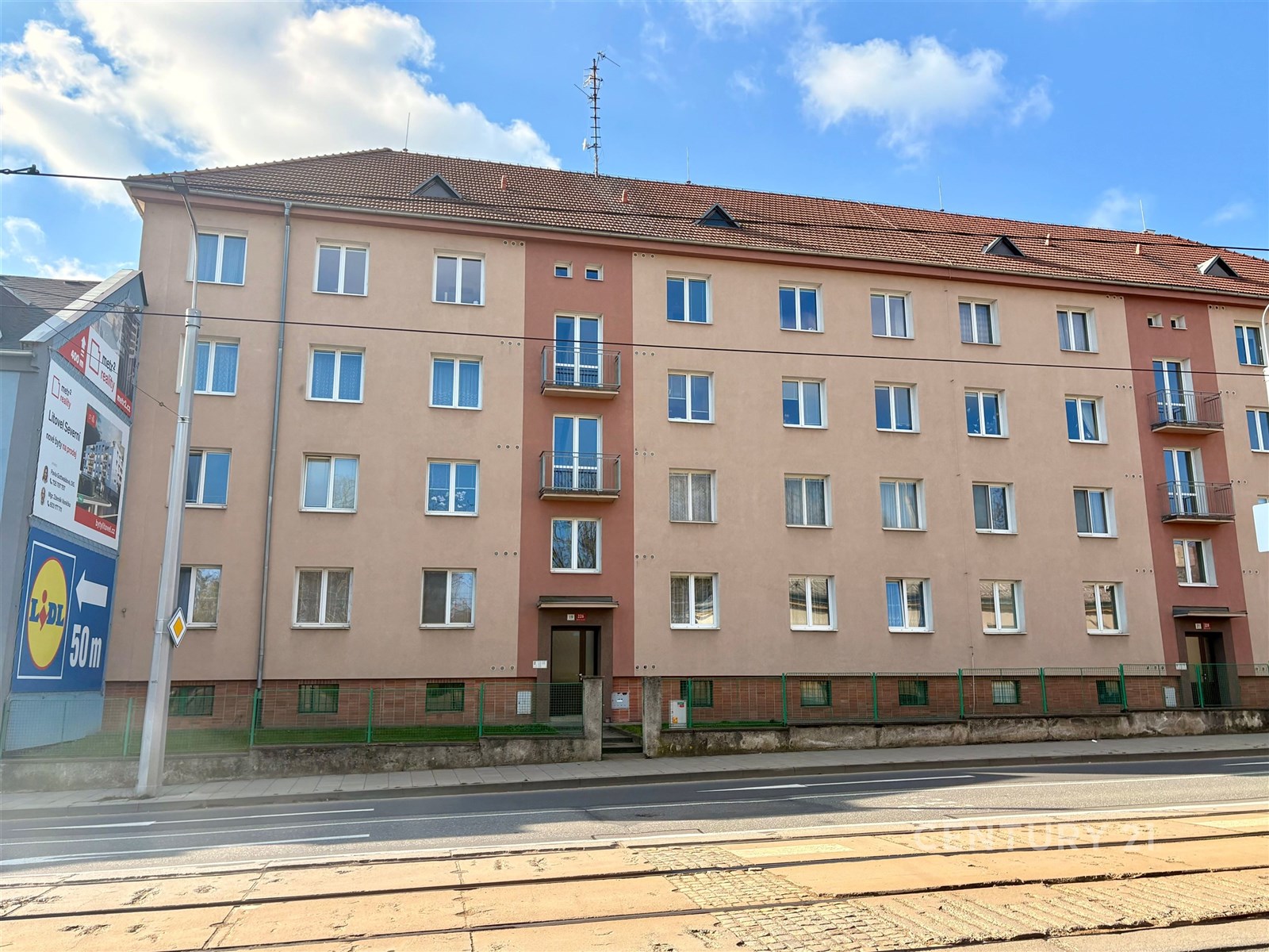 Čtyřpodlažní bytový dům s cihlovou fasádou, nová plastová okna a rekonstruovaná střecha, nachází se v blízkosti tramvajové trati.