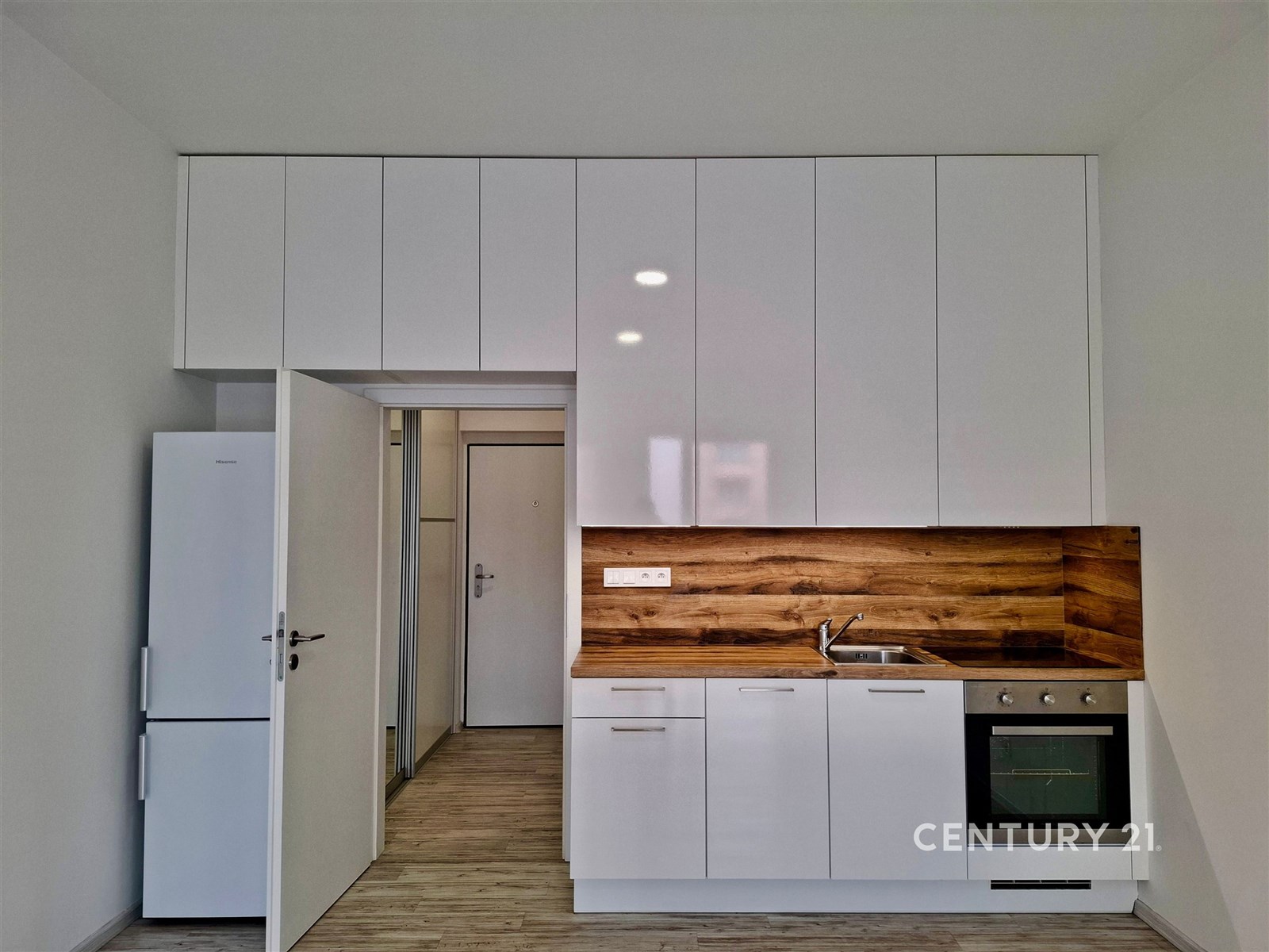 Malá moderní kuchyň s bílými skříněmi, dřevěným ob