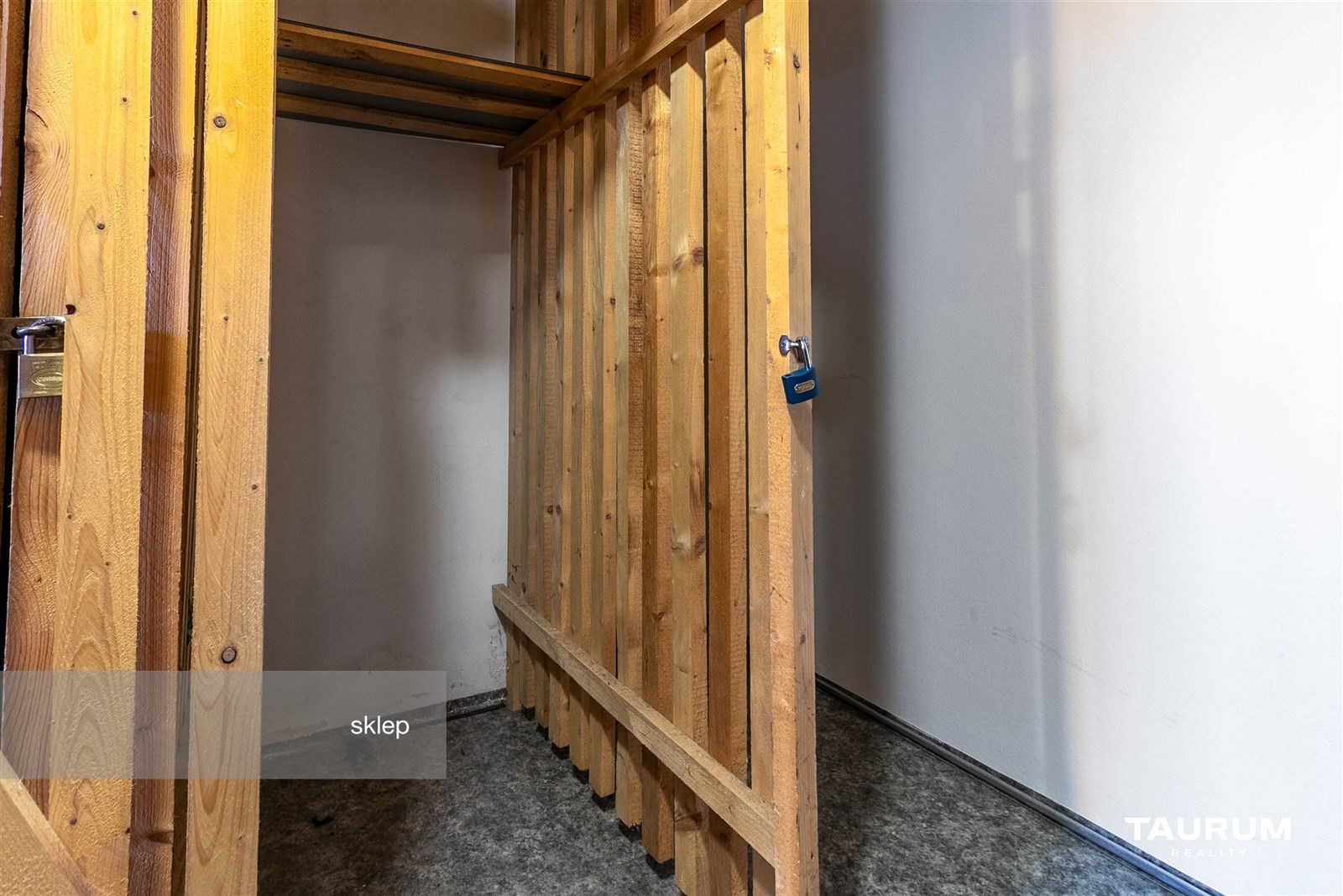 Malý sklep s dřevěnými dveřmi a betonovou podlahou