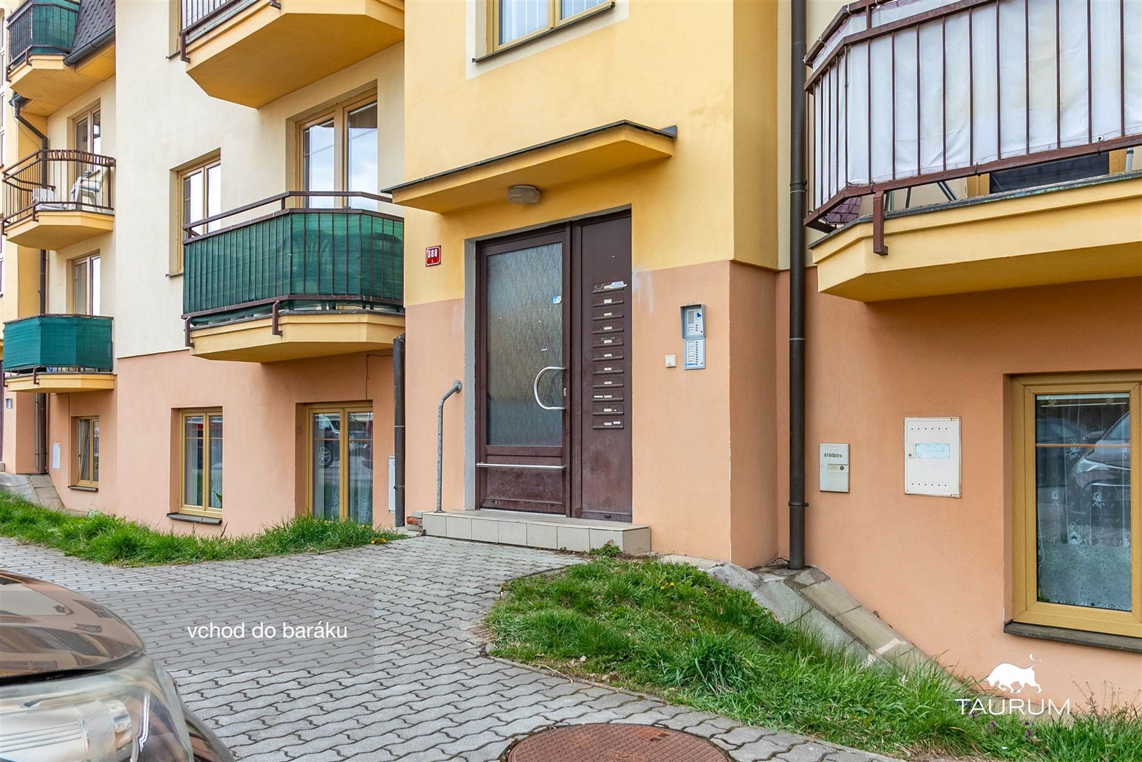 Vchod do bytového domu s moderními okny a balkóny,